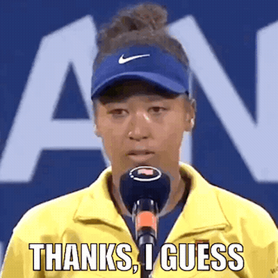 A Woman Wearing A Yellow Jacket And A Blue Hat Is Talking Into A Microphone And Saying Thanks , I Guess . GIF