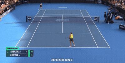 A Woman Wearing A Yellow Nike Tank Top Stands In Front Of A Scoreboard GIF