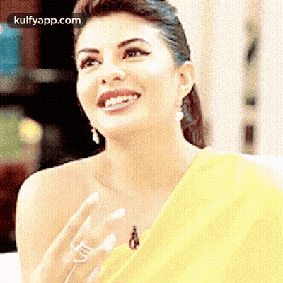 A Woman Wearing A Yellow Saree And A Ring Is Smiling . GIF