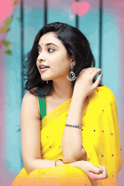 A Woman Wearing A Yellow Saree And Earrings Is Looking To The Side GIF