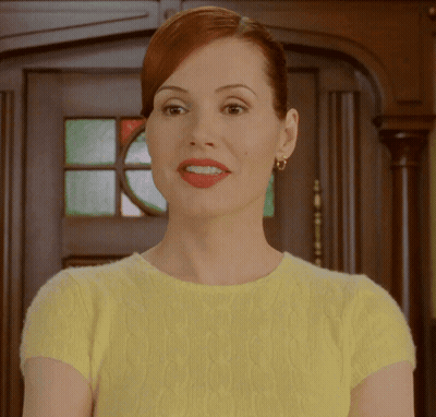 A Woman Wearing A Yellow Sweater And Red Lipstick Is Smiling GIF