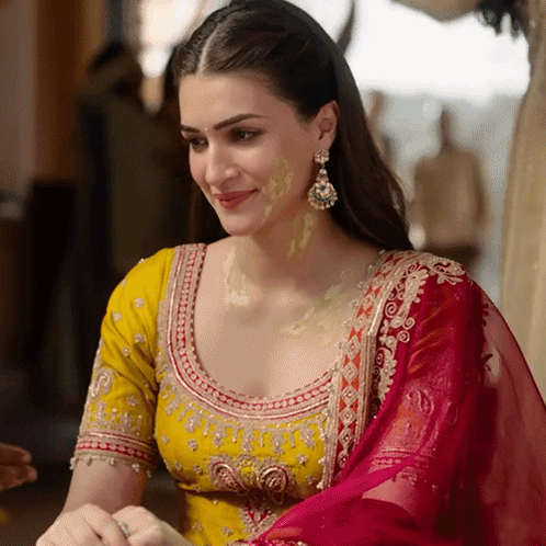 A Woman Wearing A Yellow Top And A Red Dupatta Smiles GIF