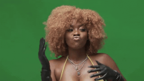 A Woman Wearing A Yellow Top And Black Gloves Is Making A Funny Face GIF