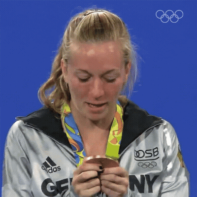 A Woman Wearing An Adidas Jacket Holds A Medal GIF