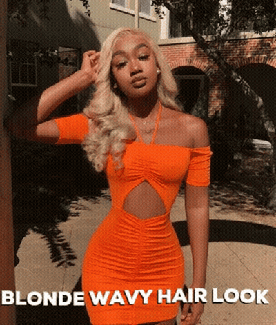 A Woman Wearing An Orange Dress With Blonde Wavy Hair GIF