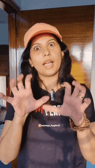 A Woman Wearing An Orange Hat Is Making A Funny Face With Her Hands GIF