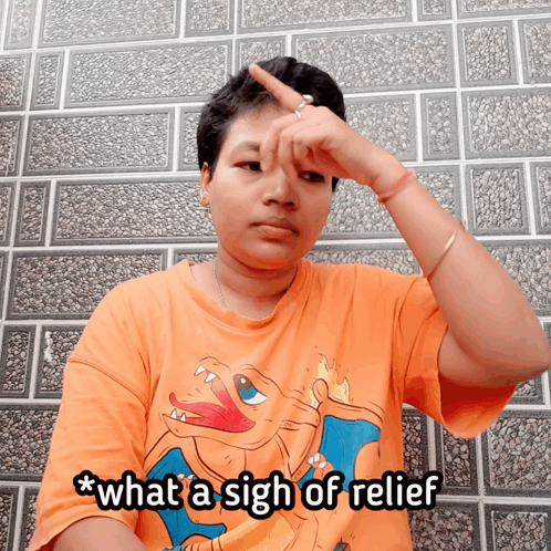 A Woman Wearing An Orange Shirt With A Pokemon On It Says What A Sigh Of Relief GIF