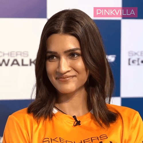 A Woman Wearing An Orange Shirt With Skechers On It GIF