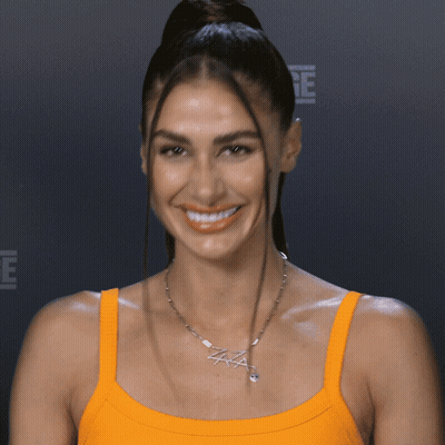 A Woman Wearing An Orange Tank Top And A Necklace That Says Aaa GIF
