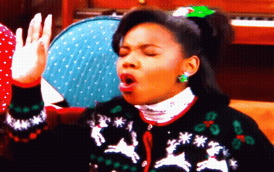 A Woman Wearing An Ugly Christmas Sweater With Reindeer And Snowflakes GIF