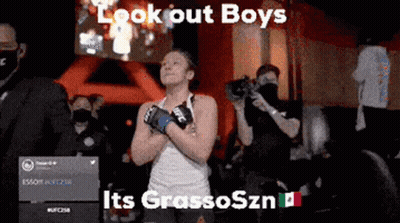 A Woman Wearing Boxing Gloves Is Standing In Front Of A Crowd And Says Look Out Boys GIF