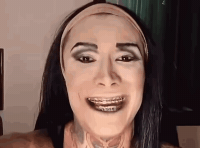 A Woman Wearing Braces And A Headband Is Smiling . GIF