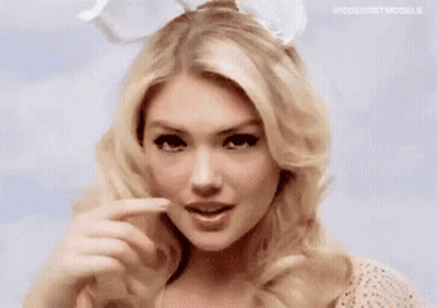 A Woman Wearing Bunny Ears Is Making A Funny Face With Her Finger . GIF