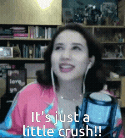 A Woman Wearing Ear Buds Is Smiling In Front Of A Microphone And The Words It 'S Just A Little Crush GIF