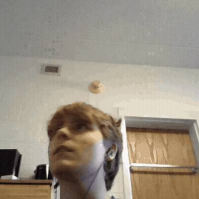 A Woman Wearing Ear Buds Looks Up At The Ceiling GIF