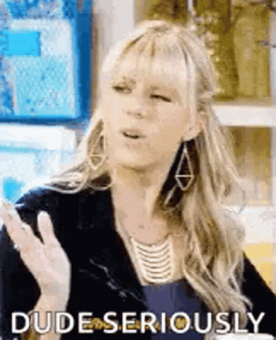 A Woman Wearing Earrings And A Necklace Is Making A Funny Face While Talking To Someone . GIF