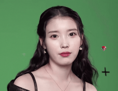 A Woman Wearing Earrings And A Necklace Looks At The Camera GIF