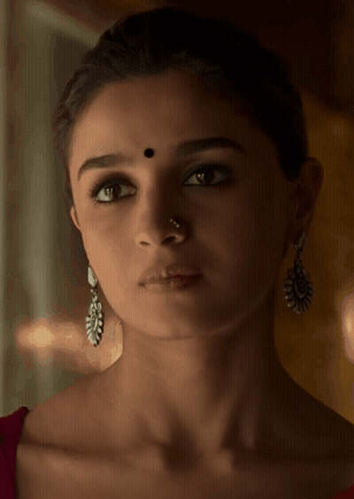 A Woman Wearing Earrings And A Nose Ring Has A Black Dot On Her Forehead GIF