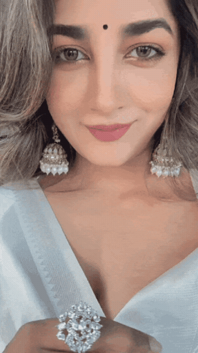 A Woman Wearing Earrings And A Ring Is Smiling GIF