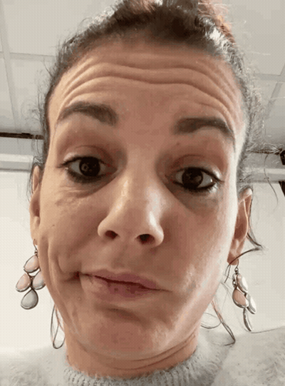 A Woman Wearing Earrings Makes A Funny Face With Her Eyes Closed GIF