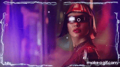 A Woman Wearing Futuristic Glasses And A Helmet Is Standing In A Dark Room . GIF