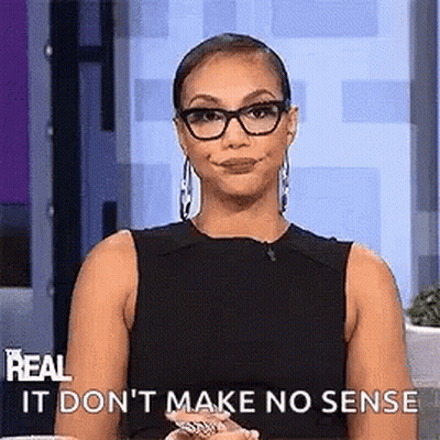 A Woman Wearing Glasses And A Black Dress Is Making A Funny Face While Sitting On A Stage . GIF