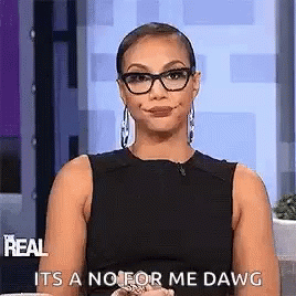 A Woman Wearing Glasses And A Black Dress Is Sitting On A Couch And Making A Face . GIF