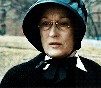 A Woman Wearing Glasses And A Black Hat With A Bow Tie GIF