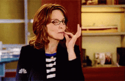 A Woman Wearing Glasses And A Black Jacket Is Eating Something . GIF