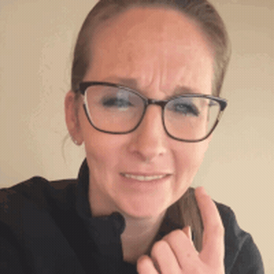 A Woman Wearing Glasses And A Black Jacket Is Making A Face GIF
