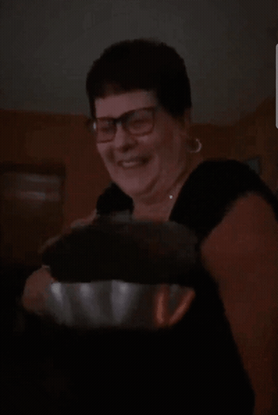 A Woman Wearing Glasses And A Black Shirt Is Smiling And Holding A Bowl GIF