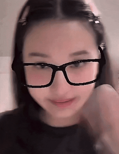 A Woman Wearing Glasses And A Black Shirt Is Smiling GIF