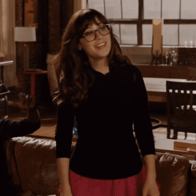 A Woman Wearing Glasses And A Black Shirt Stands In A Living Room GIF