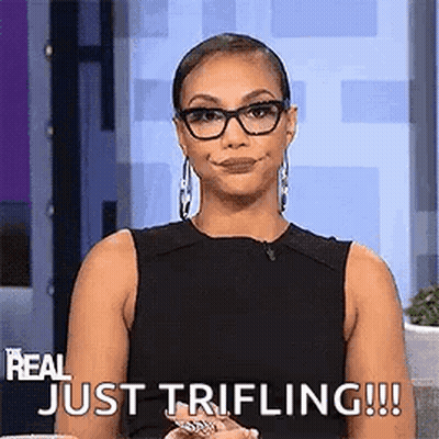 A Woman Wearing Glasses And A Black Tank Top Is Sitting On A Couch And Smiling . GIF
