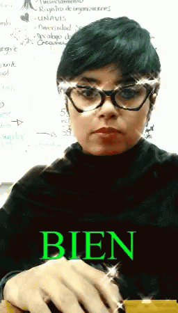 A Woman Wearing Glasses And A Black Turtleneck Has The Word Bien Written In Green GIF