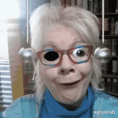 A Woman Wearing Glasses And A Blue Shirt Is Making A Funny Face GIF