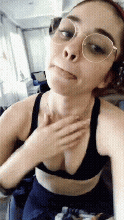 A Woman Wearing Glasses And A Bra Is Taking A Selfie GIF