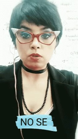 A Woman Wearing Glasses And A Choker Has A No Se Sticker On Her Chest GIF