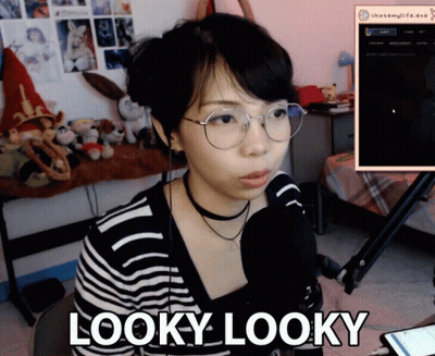 A Woman Wearing Glasses And A Choker Is Sitting In Front Of A Microphone And Says Looky Looky GIF