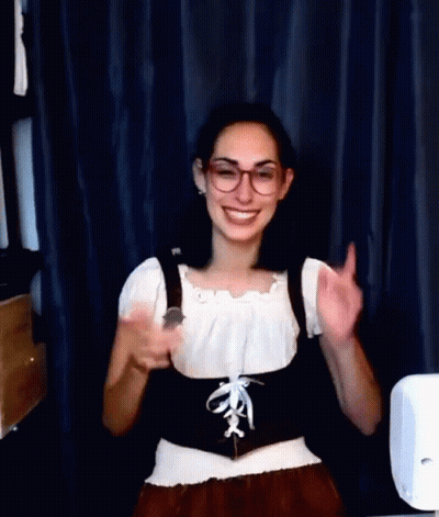 A Woman Wearing Glasses And A Corset Is Smiling And Giving A Thumbs Up Sign . GIF