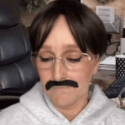 A Woman Wearing Glasses And A Fake Mustache Is Making A Funny Face GIF