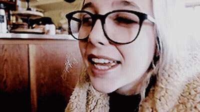A Woman Wearing Glasses And A Fur Coat Smiles At The Camera GIF