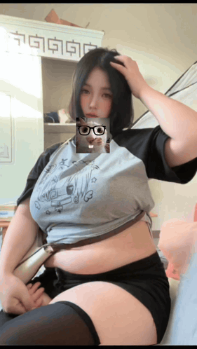a woman wearing glasses and a gray shirt has a picture of a hamster on her face