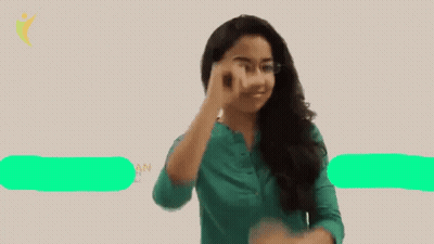 A Woman Wearing Glasses And A Green Shirt Points Her Finger Up GIF