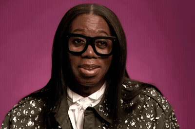 A Woman Wearing Glasses And A Jacket With A Floral Pattern GIF