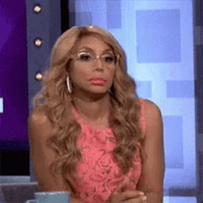 A Woman Wearing Glasses And A Pink Dress Is Sitting In Front Of A Television Screen . GIF