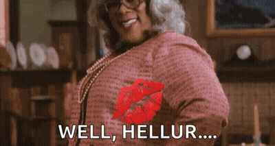 A Woman Wearing Glasses And A Pink Shirt Is Giving A Kiss With The Words `` Well , Hellur ... '' . GIF