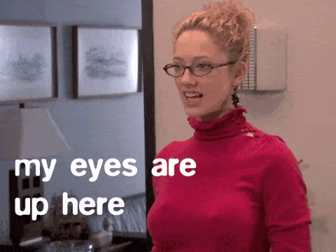 A Woman Wearing Glasses And A Pink Turtleneck Says My Eyes Are Up Here GIF