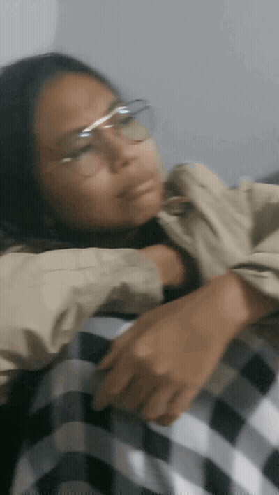 A Woman Wearing Glasses And A Plaid Shirt Is Laying Down GIF