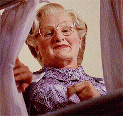 A Woman Wearing Glasses And A Purple Shirt Is Looking Out A Window GIF